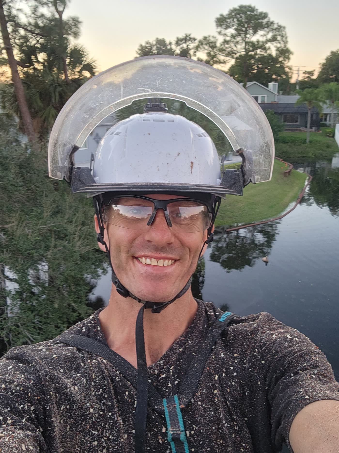 Crew member in climbing harness and hard hat elevated over a Florida yard